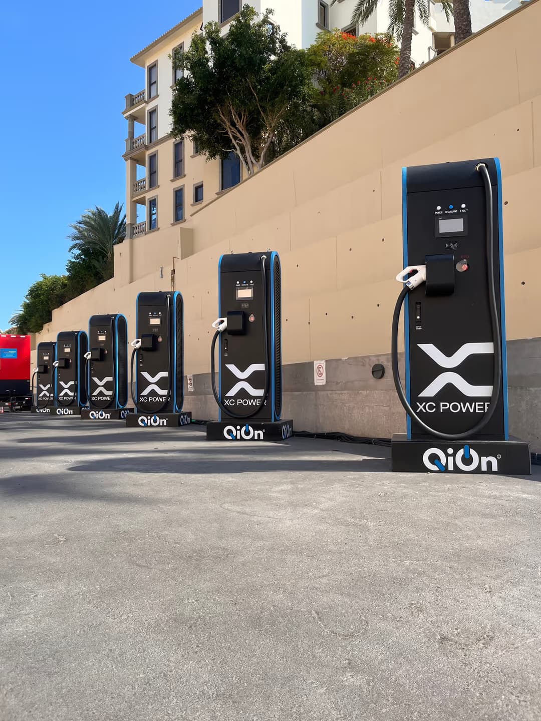 A row of six QiOn Maveriq DC fast chargers installed at the Los Cabos site, connected to a mobile off-grid power unit, ready to charge the Porsche Cayenne Electric fleet